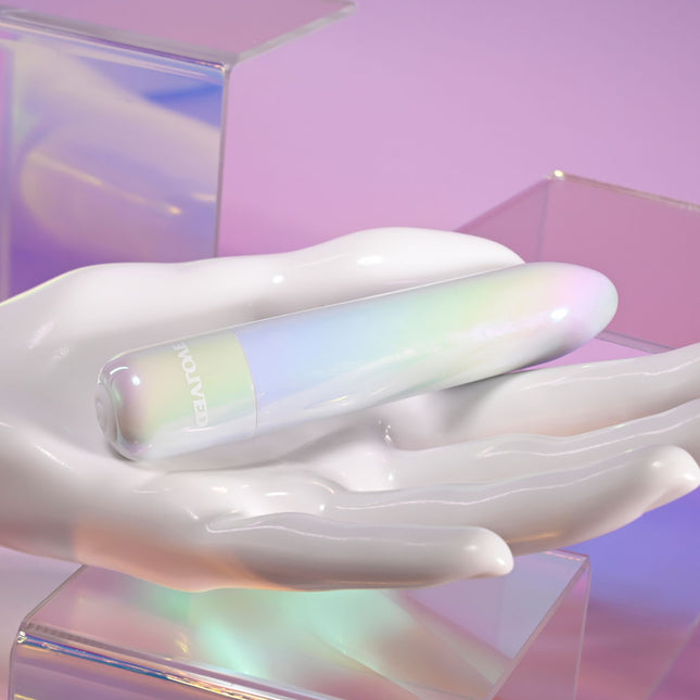 Evolved EASY DOES IT Pearlescent White Lipstick Vibrator on a white hand with a colorful background