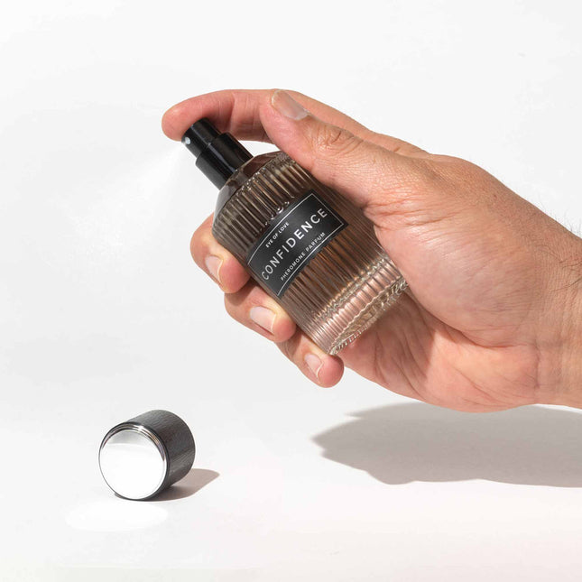 Hand holding a perfume bottle labeled 'Confidence' on a white background