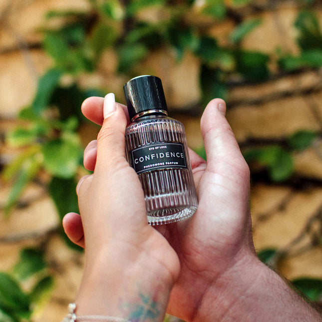 Hand holding a small bottle labeled 'Confidence' against a natural background