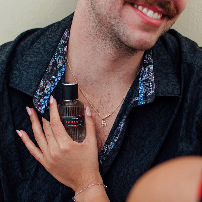 Person holding a bottle of 'Romantic' cologne with a blurred background