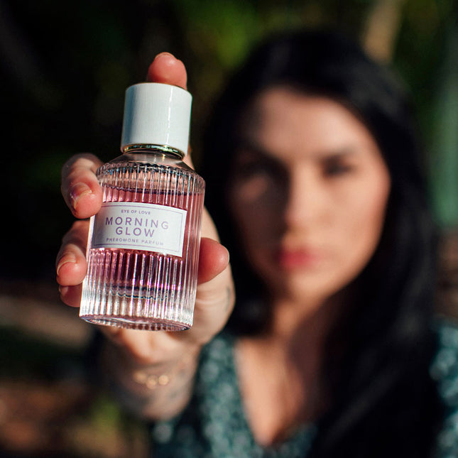 Person holding a bottle labeled 'Morning Glow' against a blurred natural background
