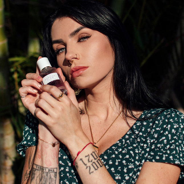 Woman holding a bottle of pheromone perfume morning glow with a natural background