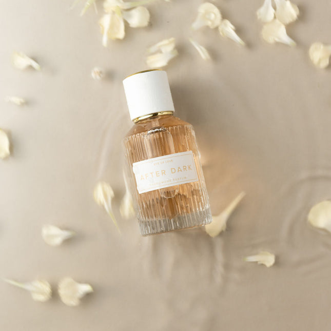 after dark Perfume bottle with a white cap and label on a beige background with small flowers.