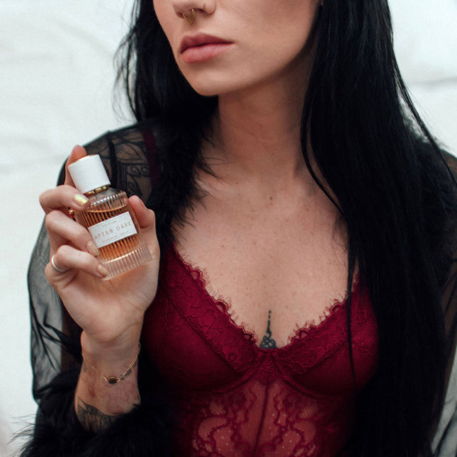 Woman holding an after dark pheromone perfume bottle with a blurred background