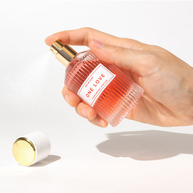 Hand holding a perfume bottle labeled 'One Love' on a white background