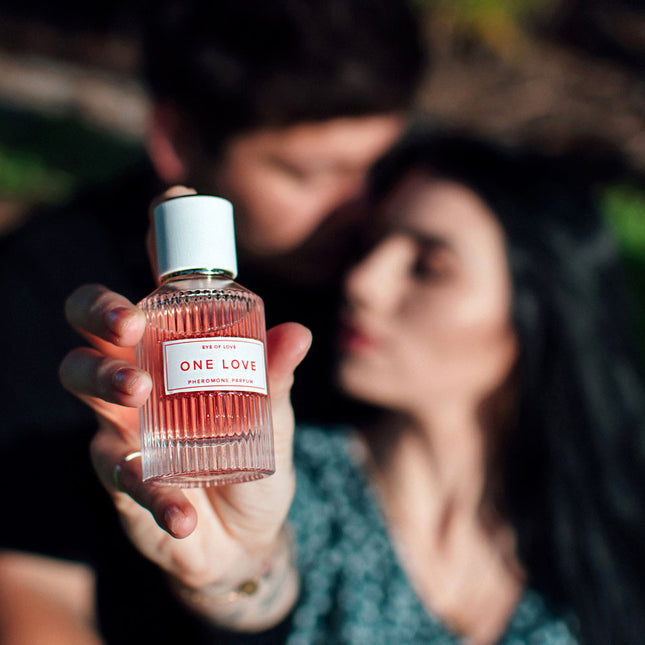 Person holding a 'One Love' perfume bottle with a blurred background