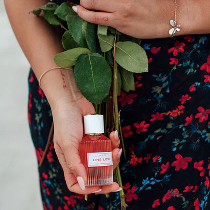 Person holding a bottle of Eye Of Love One Love Pheromone Perfume - 50ml with green leaves