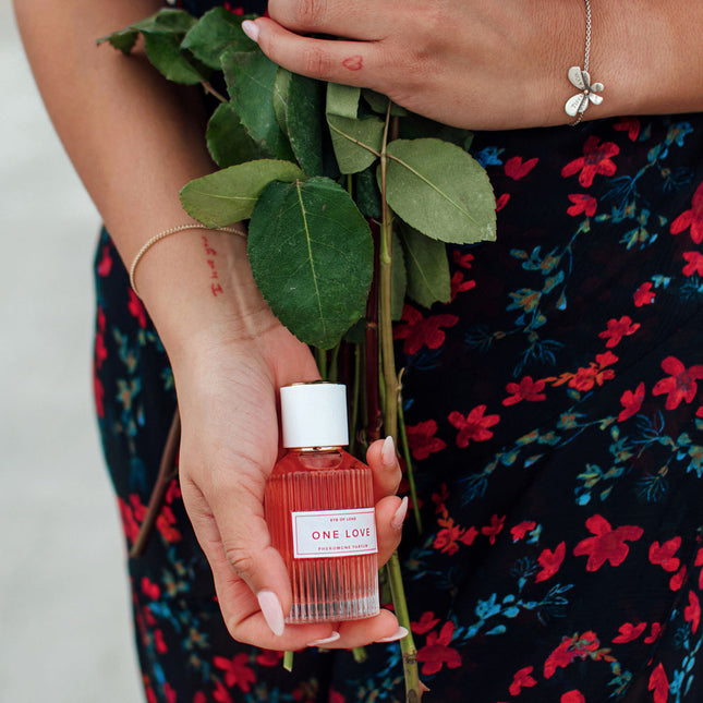 Person holding a bottle of Eye Of Love One Love Pheromone Perfume - 50ml with green leaves