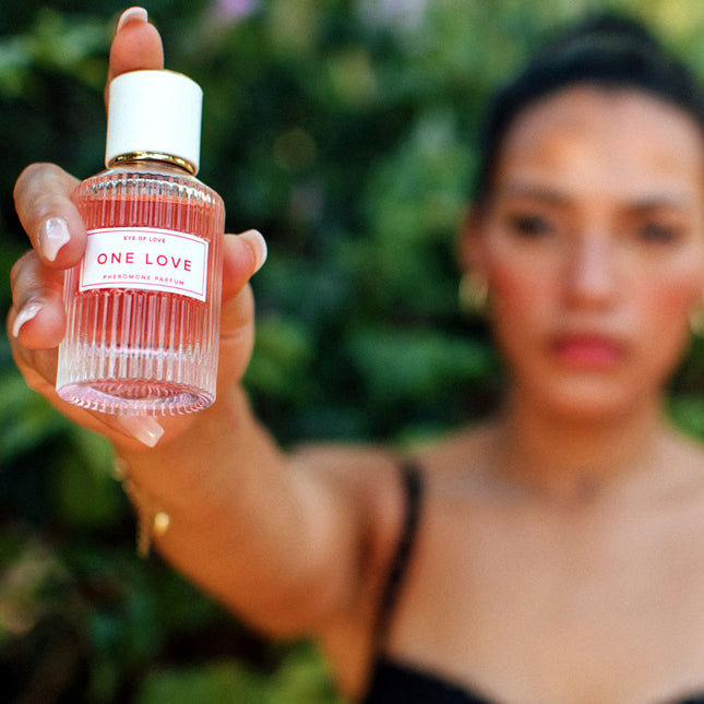Person holding a 'One Love' perfume bottle with a blurred background