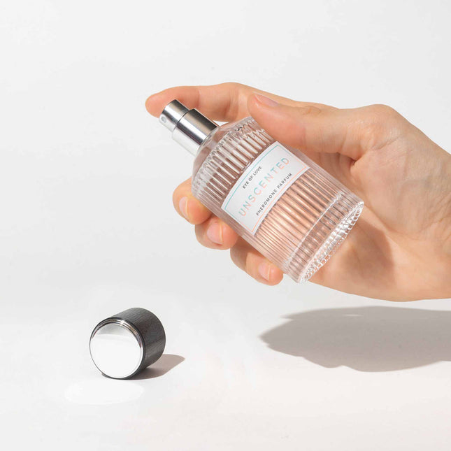 Hand holding a clear spray bottle Eye Of Love Unscented Pheromone Perfume - 50ml on a light background