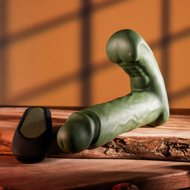 Gender X THE HUNK Green Thrusting Vibrator front view with remote control on brown table