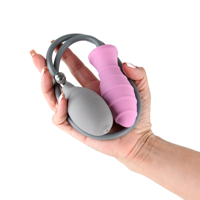 Hand holding a gray and pink silicone Inya Inflatable Butt Plug on a white background